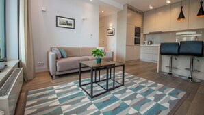 A modern living room with a sofa, a coffee table, and a kitchen in the background.