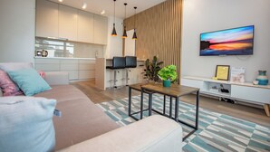 A modern living room with a sofa, a coffee table, and a TV mounted on the wall.