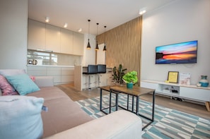 Una sala de estar moderna con un sofá, una mesa de centro y un televisor montado en la pared.