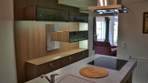 A modern kitchen with a built-in microwave, a glass shelf, and a countertop with a woven placemat.