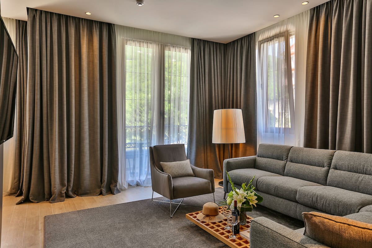 Un salon moderne avec un canapé gris, un fauteuil en cuir et une table basse ornée d’un vase de fleurs.
