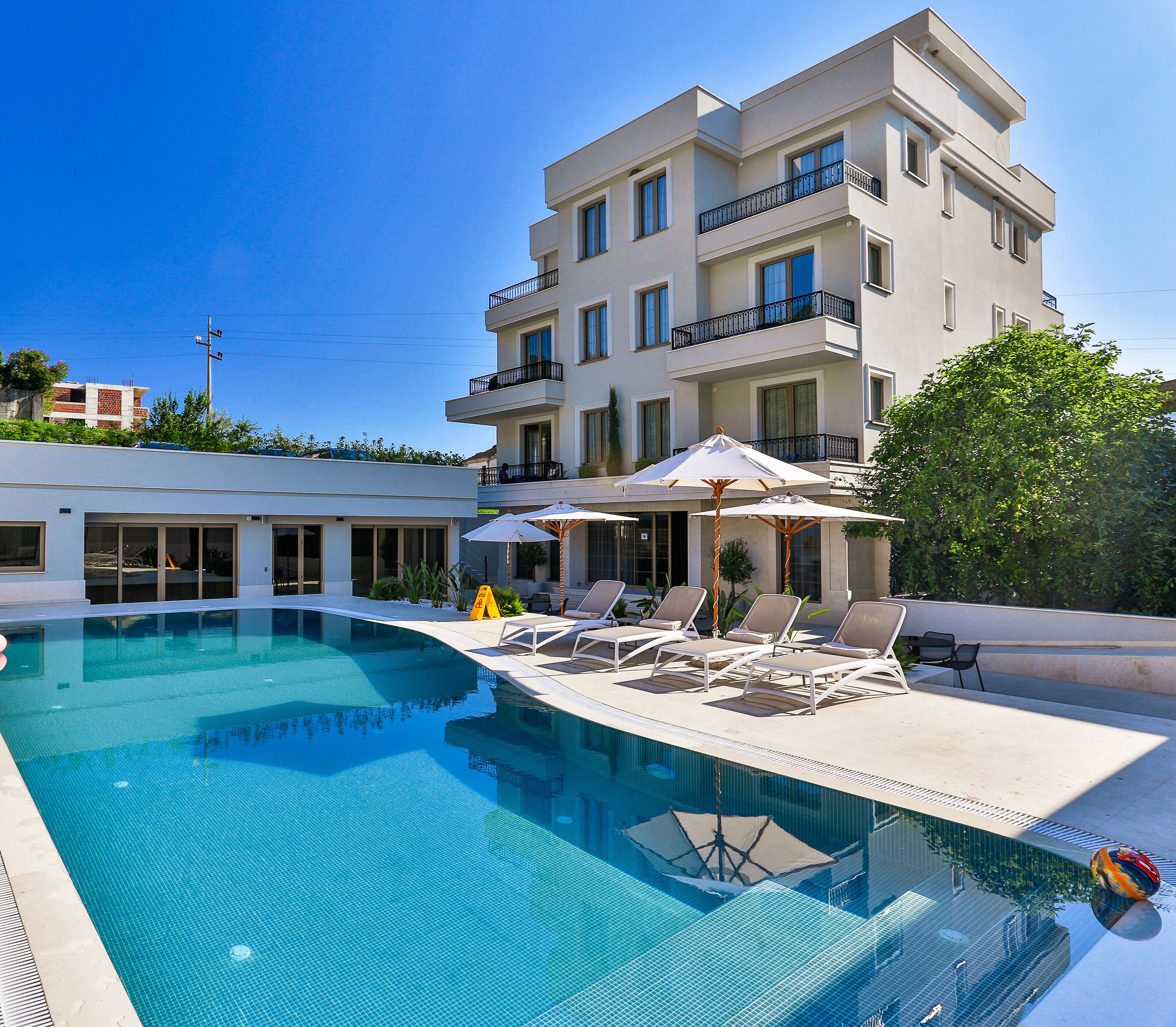 Un hôtel moderne doté d’une piscine, de chaises longues et de parasols.