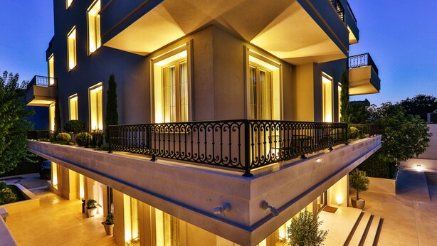 Un edificio moderno con balcón, ventanas amplias e iluminación exterior.