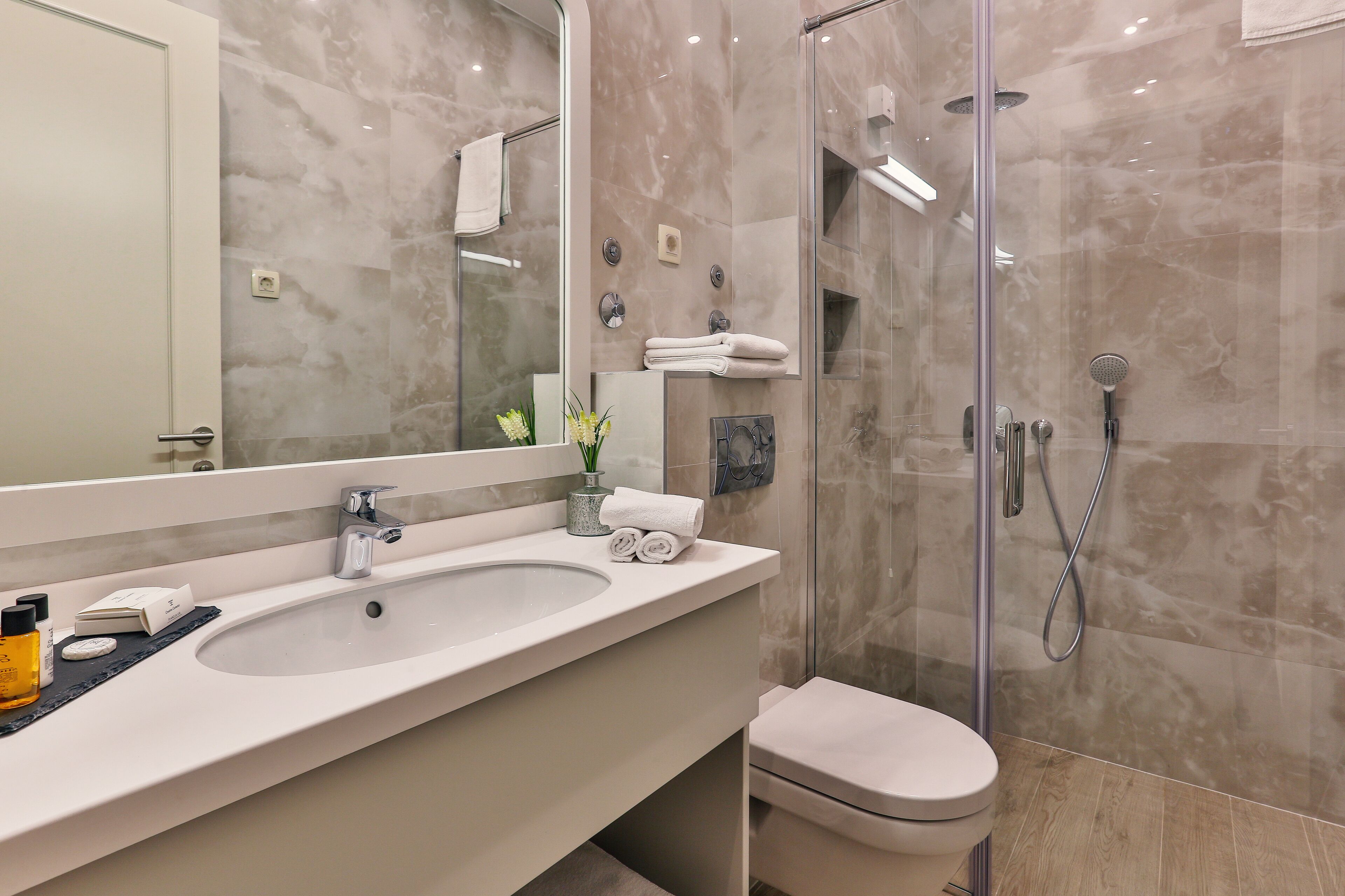 Un baño moderno con un lavamanos grande, ducha con mampara de vidrio y un inodoro.