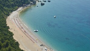 Vista aérea de una zona costera con playa, costa rocosa y colinas verdes exuberantes.