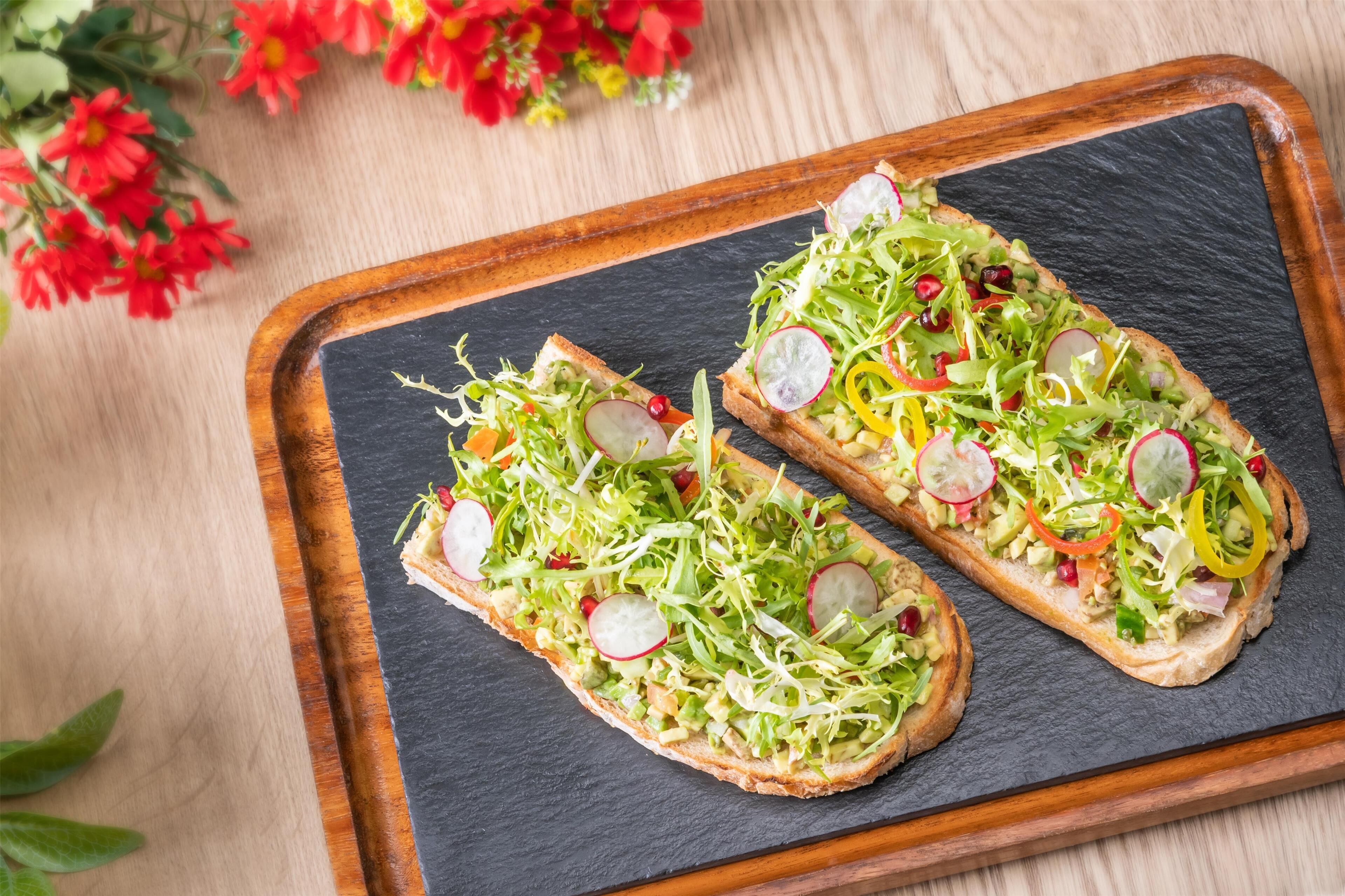 Two open-faced sandwiches on a slate board.