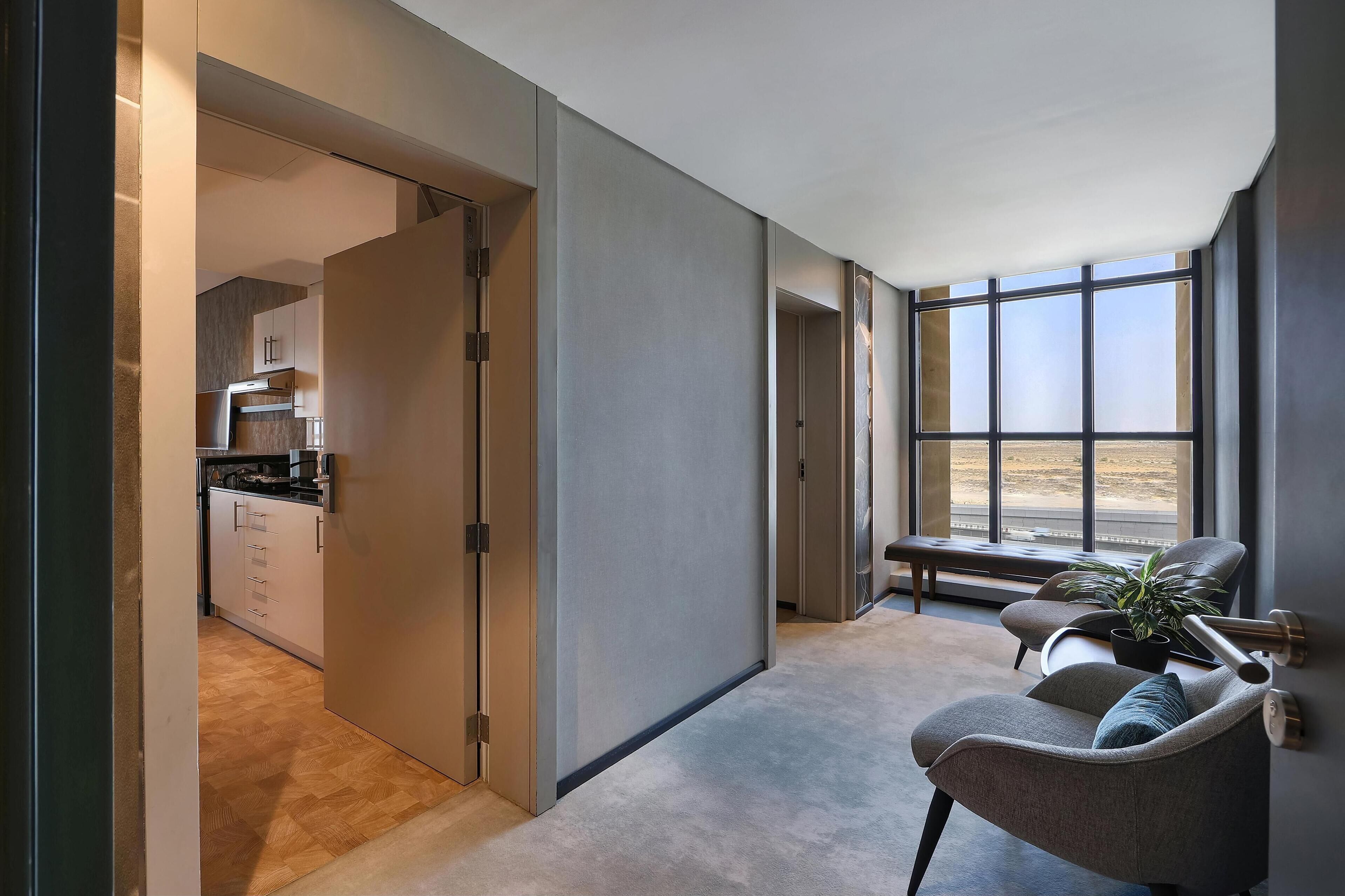 Un interior moderno con una cocina, un área de estar con una planta y ventanas amplias.