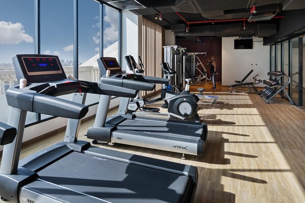 Un gimnasio con cintas de correr, elípticas y equipos de pesas.
