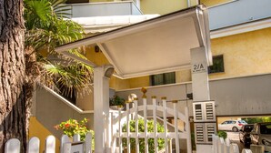 A gated entrance to a building with a tiled pathway leading to a covered area. - Residence California (Jesolo)