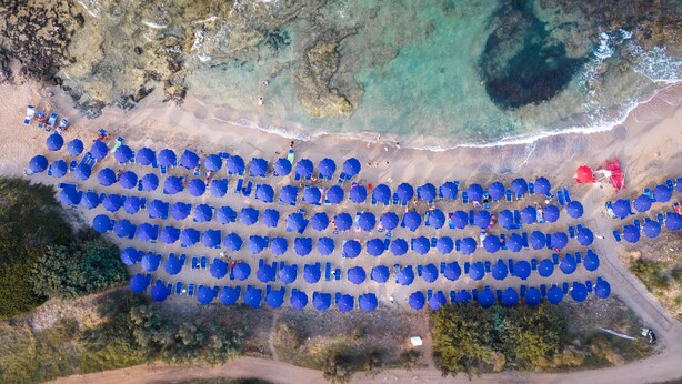An aerial view of a beach with rows of blue umbrellas and a few red tents. - Meditur Puglia by Itafirst Hotels (Carovigno)