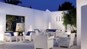 A modern outdoor patio with white furniture and stone accents. - Meditur Puglia by Itafirst Hotels (Carovigno)