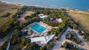 An aerial view of a resort with a swimming pool, tennis courts, and a parking area. - Meditur Puglia by Itafirst Hotels (Carovigno)