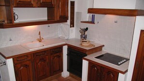 Una cocina con armarios de madera, un lavamanos blanco, un lavavajillas negro y un salpicadero de azulejos.