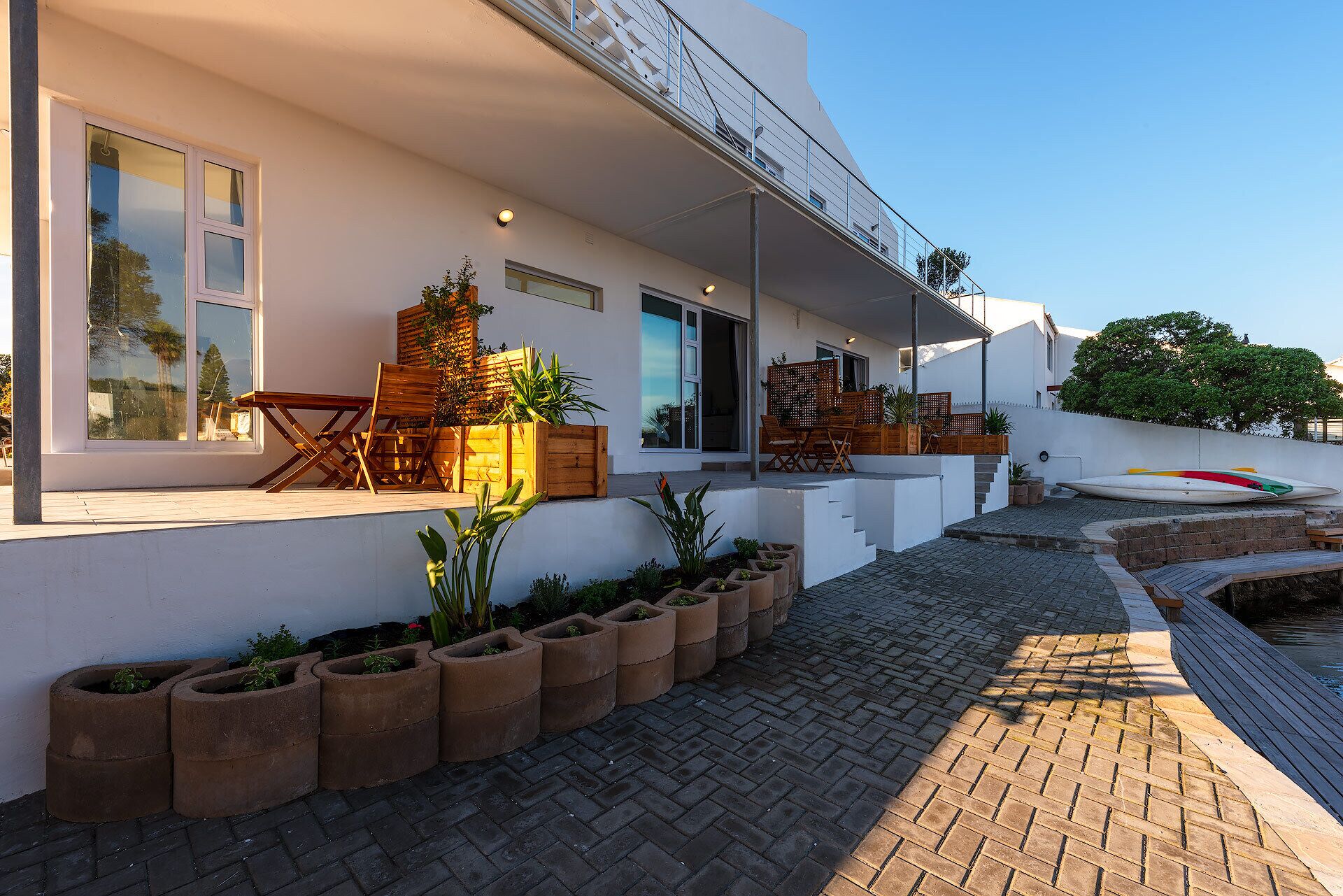 A modern house with a patio, outdoor seating, and potted plants.