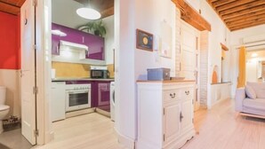 Une cuisine moderne avec des armoires blanches, un plan de travail violet et un plafond en bois.