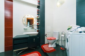 Une salle de bain moderne avec un meuble-lavabo noir, un lavabo blanc et des toilettes avec un abattant rouge.