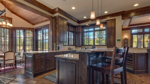 A spacious kitchen with dark wood cabinets, a large island, and pendant lighting.