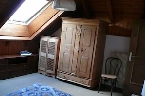 A room with a sloped ceiling, wooden wardrobe, and a radiator.