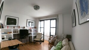 Ein Wohnzimmer mit einer Couch, Sesseln, einem Fernseher und Regalen mit Büchern und Dekoration.