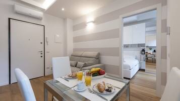 Een moderne hotelkamer met een zithoek, een bank, een bed en een keuken op de achtergrond.