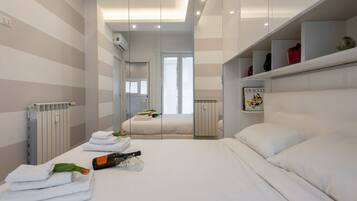 Een moderne hotelkamer met een groot bed, een nachtkastje met een fles en glazen, een radiator en een raam met uitzicht.