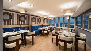 Ein Restaurant mit Holzböden, blau gepolsterten Sitzelementen und runden Spiegeln an den Wänden.