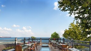 Eine Außen-Terrasse mit Sitzgelegenheiten und Tischen mit Blick aufs Meer.