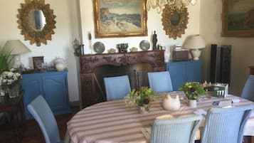 Ein Esszimmer mit einem runden Tisch, blauen Stühlen, einer Kristallleuchter und dekorativen Spiegeln.