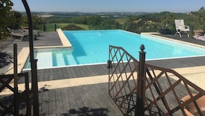 A rectangular swimming pool with a wooden deck and a metal gate. - Chambres d'Hotes Las Caneres (Castelnau-d'Arbieu)