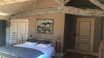A bedroom with a bed, a painting, a bedside table, and a chair.