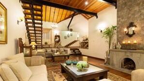A spacious living room with a high ceiling, a staircase, a fireplace, and a cozy seating area. - Manuel Manor (Labukele)