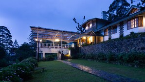 A large house with a covered porch, stone walls, and a well-maintained garden. - Manuel Manor (Labukele)