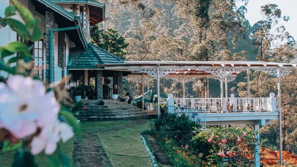 A house with a porch, surrounded by a garden and trees. - Manuel Manor (Labukele)