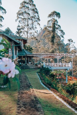 A house with a porch, surrounded by a garden and trees. - Manuel Manor (Labukele)