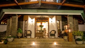 A stone staircase leading to a covered entrance with a table and chairs in front, surrounded by potted plants and candles. - Manuel Manor (Labukele)