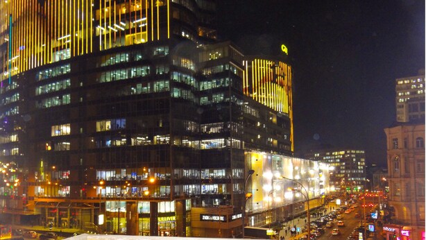 A nighttime cityscape with a prominent building featuring illuminated vertical lines and multiple floors. - KyivHome Basseyna 17 City centre (Kyiv)