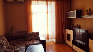A living room with a sofa, a small table, a TV, and a decorative giraffe. - KyivHome Basseyna 17 City centre (Kyiv)