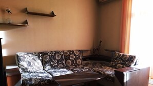 A sectional sofa with a floral pattern, a wooden coffee table, and a giraffe decoration on a wooden floor. - KyivHome Basseyna 17 City centre (Kyiv)