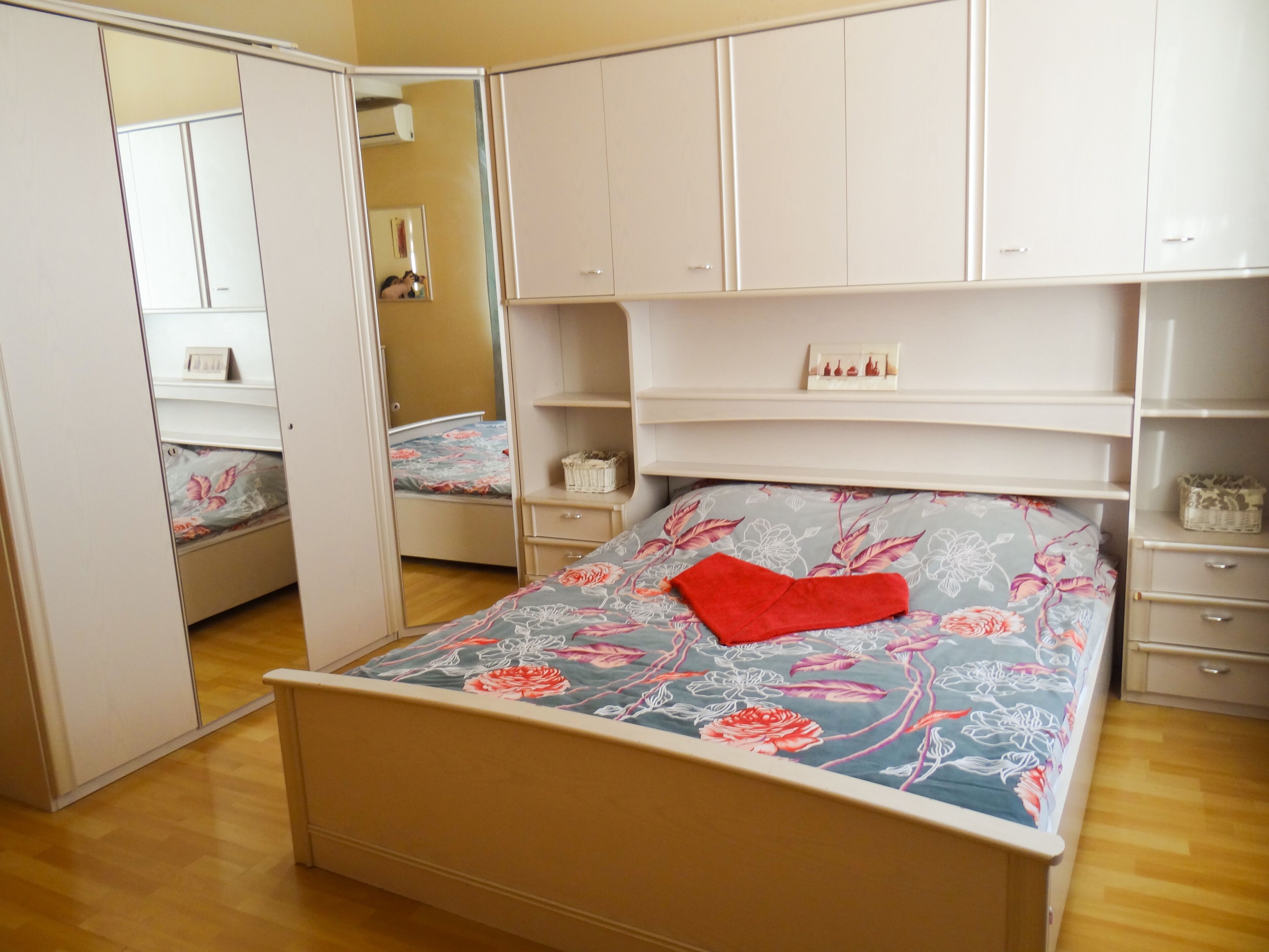 A bedroom with a bed, a wardrobe, and a mirror.