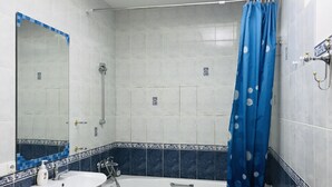 Une salle de bain avec une baignoire, un lavabo et un rideau de douche.