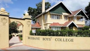 En byggnad med en skylt som visar texten ”BRISBANE BOYS’ COLLEGE” och en gångväg som leder till entrén.