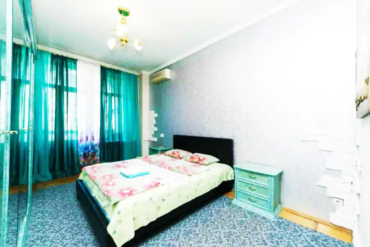 A bedroom with a bed, a nightstand, a ceiling fan, and a window with curtains.