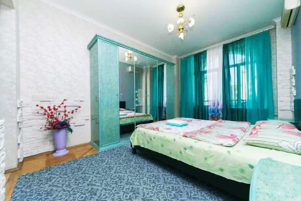 A bedroom with a bed, a mirror, a dresser, and a potted plant.