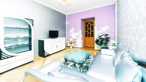 A living room with a sofa, a glass coffee table, a TV on a cabinet, and a door leading to another room. - KyivHome at Khreschatyk (Kyiv)