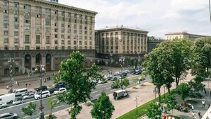 A large building with multiple floors and a central courtyard with trees and a parking area. - KyivHome at Khreschatyk (Kyiv)