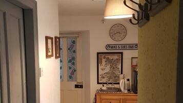Un couloir avec un radiateur, une horloge et une lampe fixée au mur.