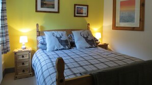 Une chambre à coucher comprenant un lit, deux tables de chevet, une commode et une tête de lit.