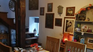 Un coin repas avec une table en bois mise pour un repas, entourée de chaises. On y trouve divers aliments et condiments.