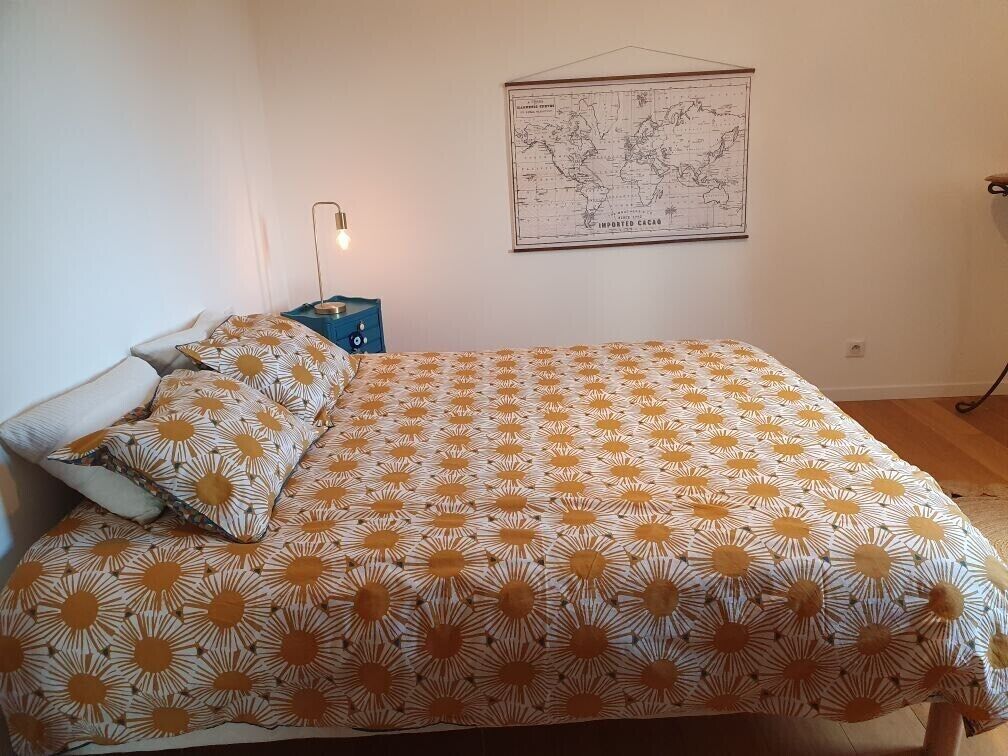 Une chambre à coucher avec un lit, une table de chevet, une lampe et une carte géographique accrochée au mur.