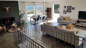 A spacious living area with a fireplace, a sofa, a television, and a balcony with a table and chairs. - Villa "Chjosella" (Santa Reparata di Balagna)